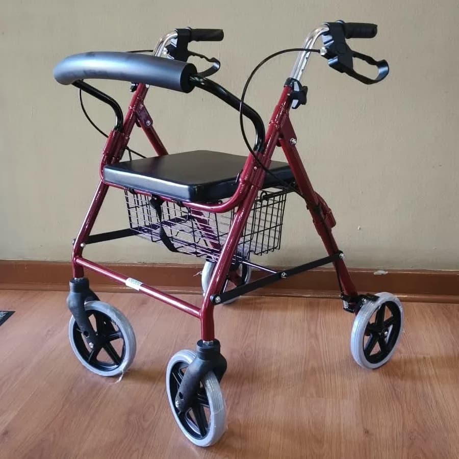 A red four-wheel rollator with a seat, a basket and hand brakes